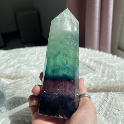 Holding a rainbow fluorite tower. Clear tip with deep purple base