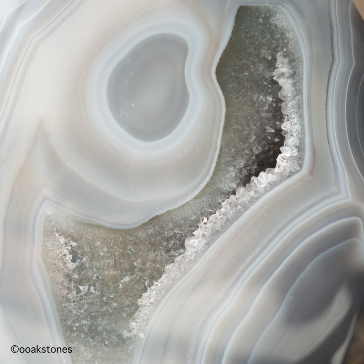 Detailed natural agate eye formation surrounded by gray chalcedony and druzy quartz