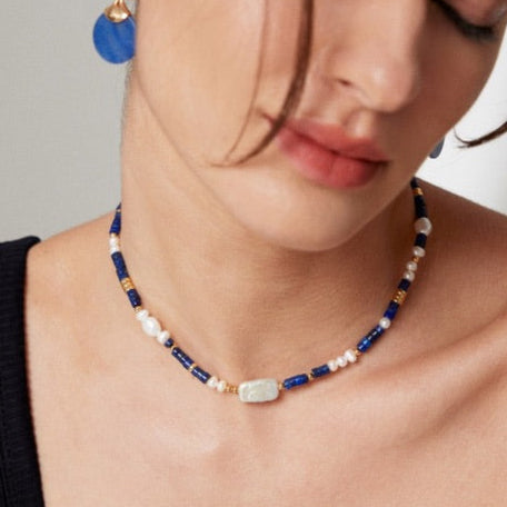 Necklace with blue and gold beads worn by a person