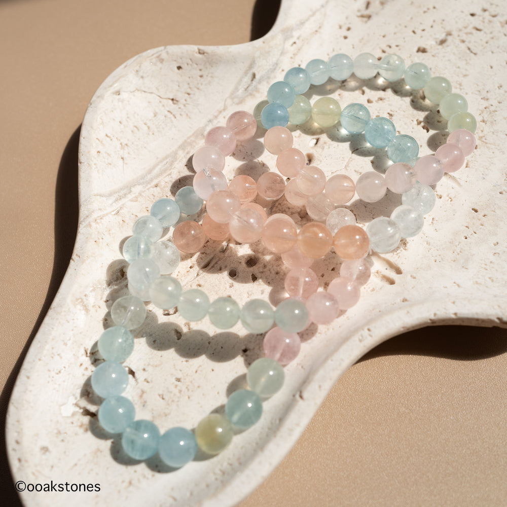 Natural Morganite bracelet with soft pastel pink, peach, aqua and champagne beryl beads from Brazil displayed on a stone tray.