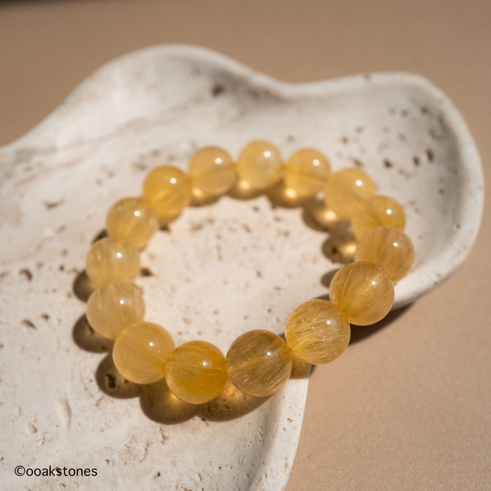 Natural Yellow Fluorite bracelet with transparent golden beads from Inner Mongolia displayed on a natural stone dish.