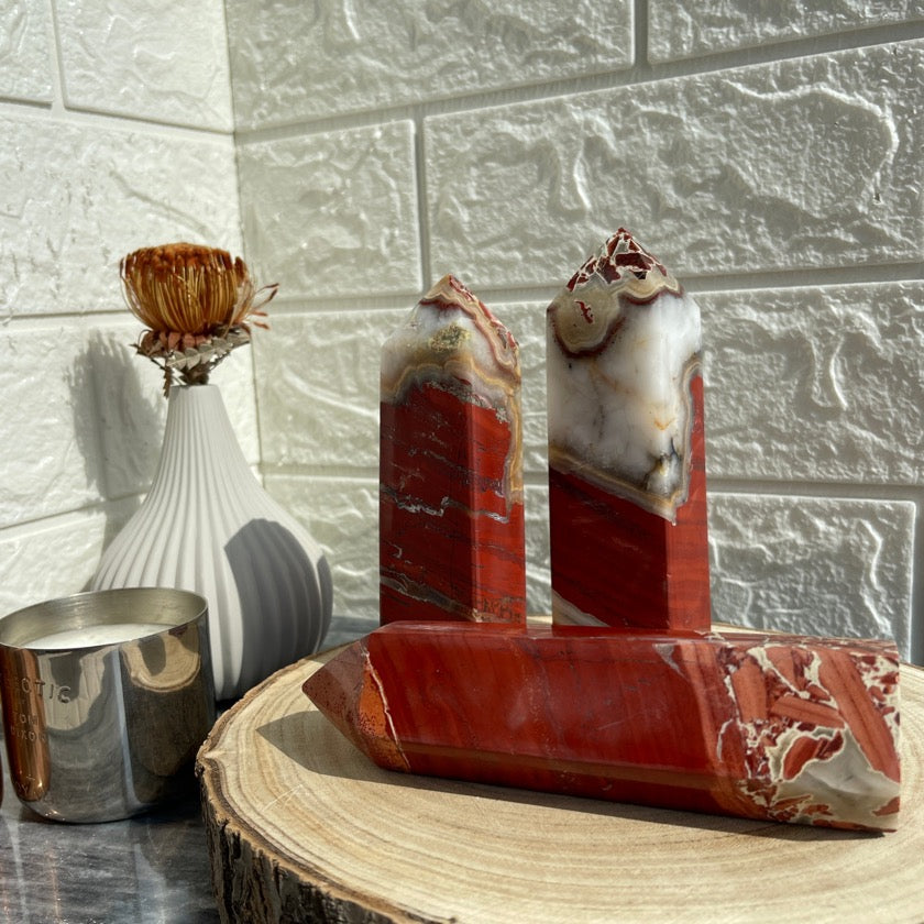 Red jasper crystals styled on top of a wood tray next to candles