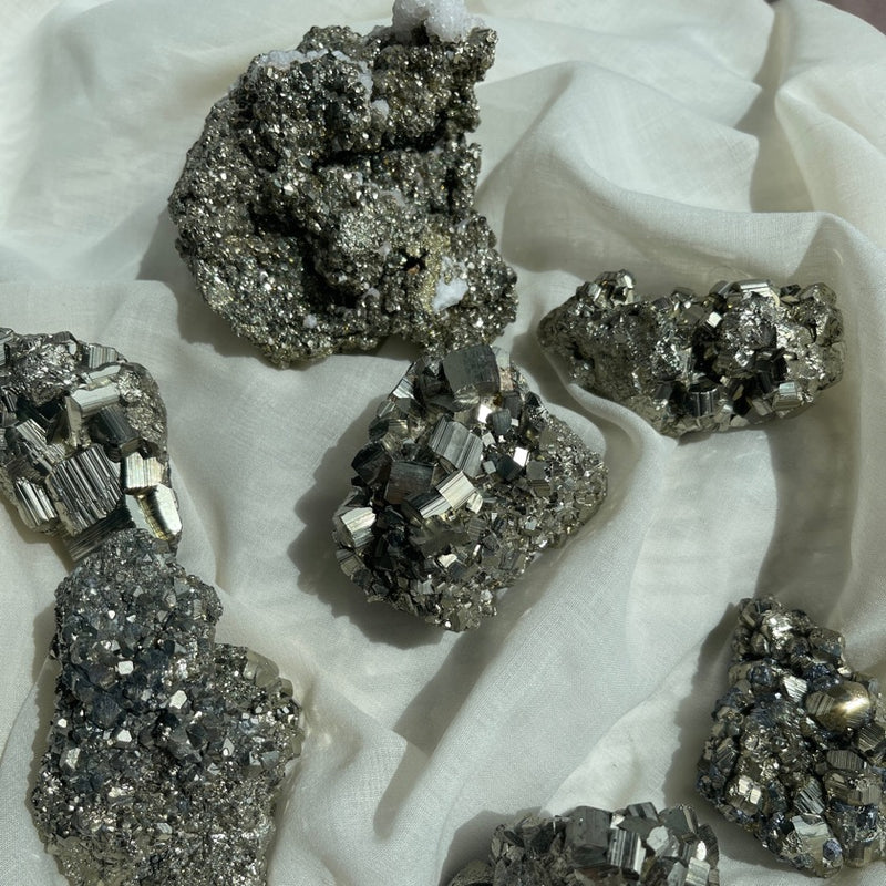 Mexican Pyrite clusters sparkles on a cream color fabric  