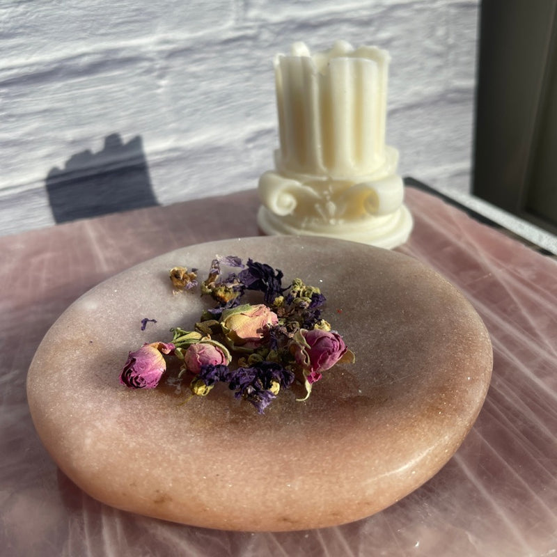 Salmon pink color pink amethyst jewelry dished with dried rose flowers in it styled on top of a rose quartz slab
